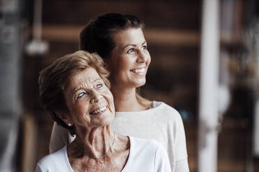 Lächelnde junge Frau und Großmutter, die zu Hause wegschauen - GUSF05530