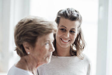 Smiling woman with brown hair looking at grandmother - GUSF05536