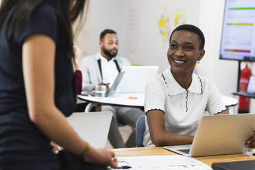 Smiling businesswoman looking at colleague in office - PNAF01108