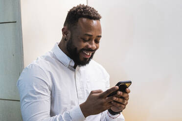 Young businessman using mobile phone in office - PNAF01150