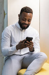 Businessman using mobile phone while sitting in office - PNAF01151