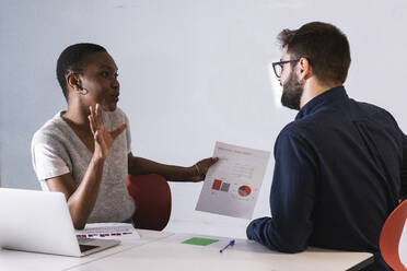 Female colleague explaining data over document to businessman at office - PNAF01183