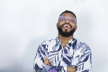 Happy young businessman with arms crossed in front of white background - PNAF01206