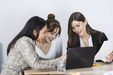 Lächelnde Unternehmerinnen arbeiten am Laptop im Büro - PNAF01210