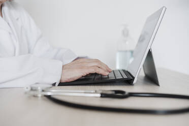 Oberärztin bei der Arbeit an einem digitalen Tablet am Schreibtisch im Krankenhaus - EBBF02812