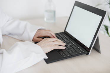 Medizinische Fachkraft mit digitalem Tablet am Schreibtisch in einer medizinischen Klinik - EBBF02813