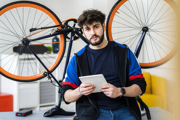 Mann hält digitales Tablet am Fahrrad zu Hause - GIOF11929