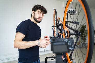 Junger männlicher Vlogger mit Fahrrad, der zu Hause ein Tutorial macht - GIOF11967