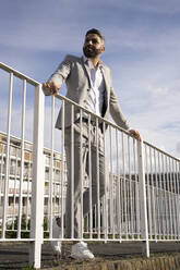 Männliche Fachkraft steht auf einem Steg am Geländer - FBAF01663