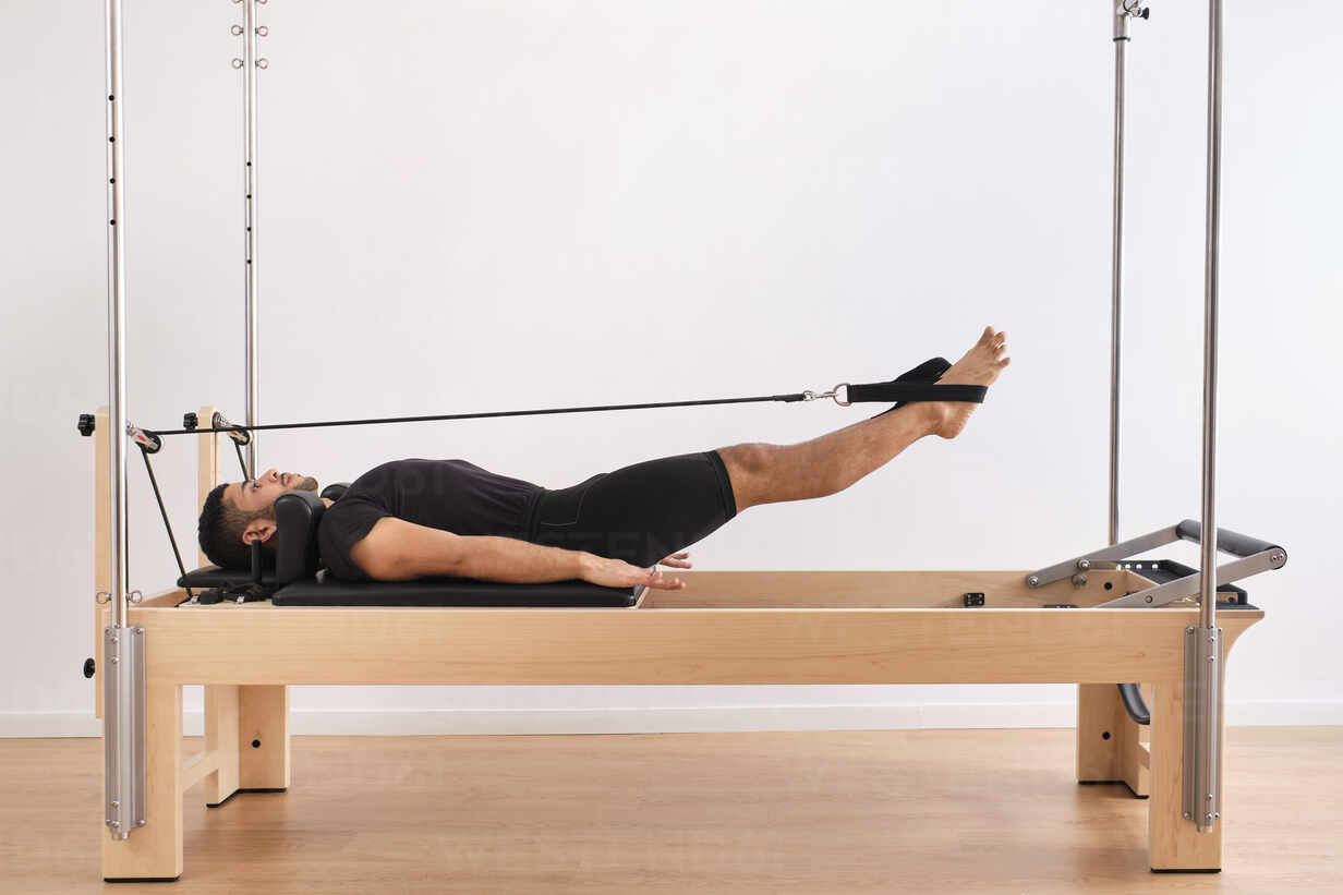 Woman on Reformer Bed Doing Hip Opening Exercises Stock Photo