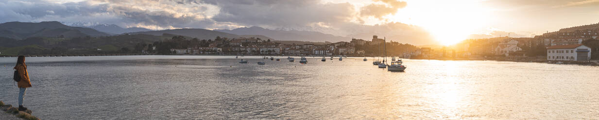 Spanien, Kantabrien, San Vicente de la Barquera, Junger Rucksacktourist beobachtet Meer bei Sonnenuntergang - JAQF00407