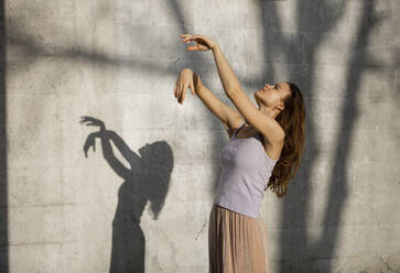 Young woman with brown hair dancing during sunny day - AXHF00221