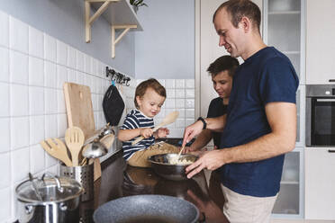 Father with cute sons preparing food in kitchen at home - VYF00420