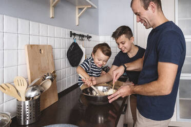 Fröhliche Söhne helfen ihrem Vater bei der Zubereitung von Speisen in der Küche zu Hause - VYF00421