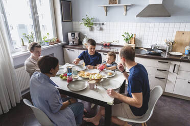 Glückliche Familie beim Essen am Esstisch in der Küche zu Hause - VYF00439