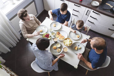 Family eating food at dining table in kitchen at home - VYF00440