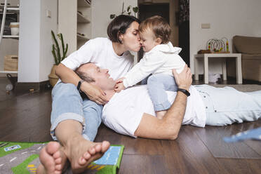 Familie umarmt süßen Sohn im Wohnzimmer zu Hause - VYF00469