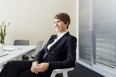 Lächelnde weibliche Business Professional Tag träumen, während auf Stuhl im Büro sitzen - MEUF02227