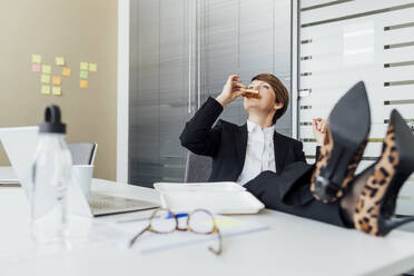 Unternehmerin beim Mittagessen am Schreibtisch im Büro - MEUF02282