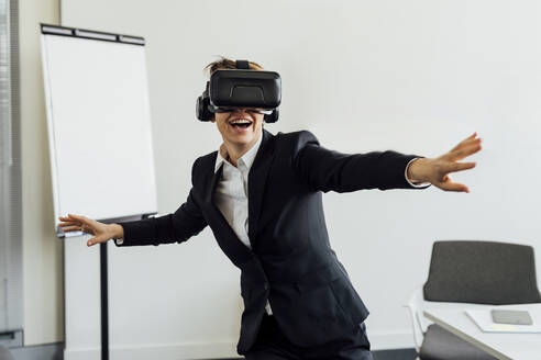 Gut gelaunte Geschäftsfrau mit Virtual-Reality-Simulator im Büro - MEUF02287