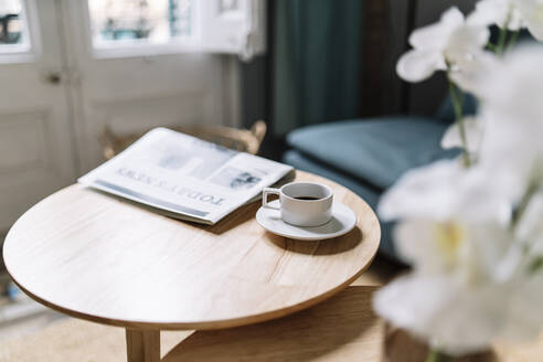 Kaffeetasse neben der Zeitung auf dem Tisch zu Hause - JCZF00540