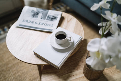 Kaffee auf Buch bei Zeitung auf Holztisch zu Hause - JCZF00542