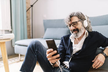 Man with headphones using smart phone at home - JCZF00569