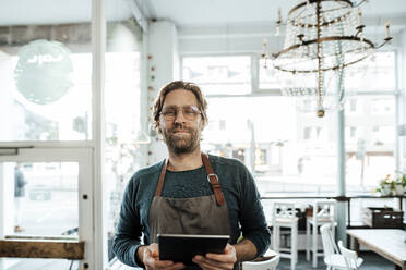 Männlicher Besitzer mit digitalem Tablet in einem Cafe - JOSEF03896