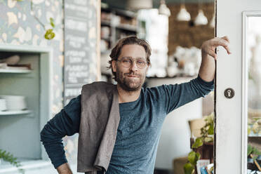 Male owner leaning on door in coffee shop - JOSEF03907