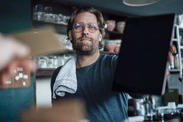 Älterer männlicher Unternehmer zeigt digitales Tablet in einem Café - JOSEF03914