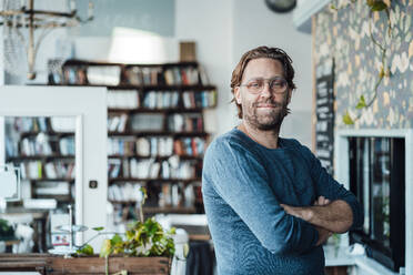 Confident male owner with arms crossed at coffee shop - JOSEF03923