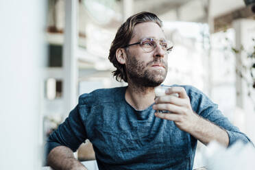 Thoughtful man with coffee cup looking away in cafe - JOSEF03942