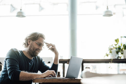 Männlicher Unternehmer mit Laptop in einem Cafe - JOSEF03944