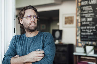 Thoughtful male entrepreneur with arms crossed in cafe - JOSEF03954