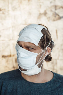 Man with protective face masks in front of wall - JOSEF03984