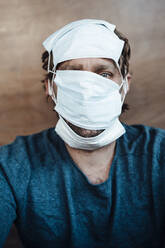 Man with protective face masks in front of wall - JOSEF03985