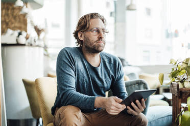 Reifer männlicher Unternehmer, der wegschaut und ein digitales Tablet in einem Café hält - JOSEF03993