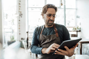 Älterer männlicher Unternehmer, der in einem Café ein digitales Tablet benutzt - JOSEF04007