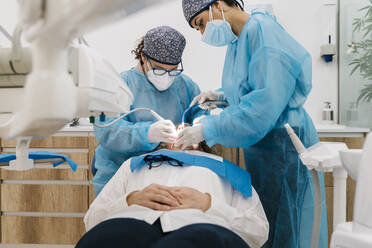 Zahnärzte mit Gesichtsschutz und Arbeitskleidung bei der Kontrolle von Patienten in der Klinik - EGAF02151