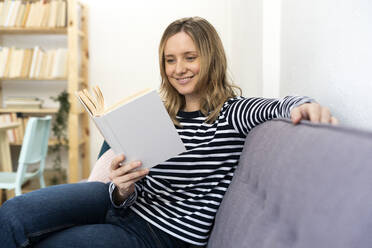 Mittlere erwachsene Frau liest zu Hause ein Buch - GIOF11992