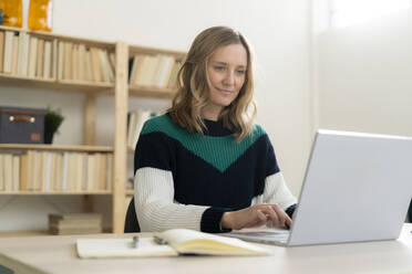 Blond mid adult woman using laptop at home - GIOF11998