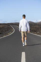 Young male tourist walking on road - SNF01191