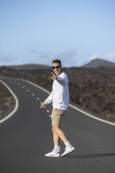 Happy male tourist gesturing while standing on road - SNF01192