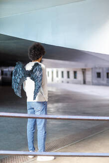 Mann mit Engelsflügeln steht vor einem Gebäude - IFRF00488