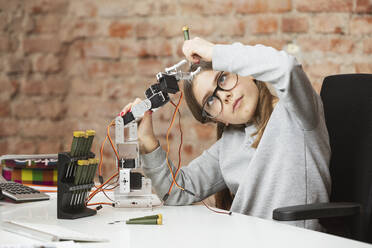 Mädchen macht wissenschaftliches Experiment mit Roboterarm am Tisch - DHEF00616