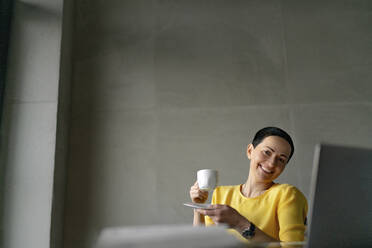 Smiling female professional having coffee in office - OGF01007