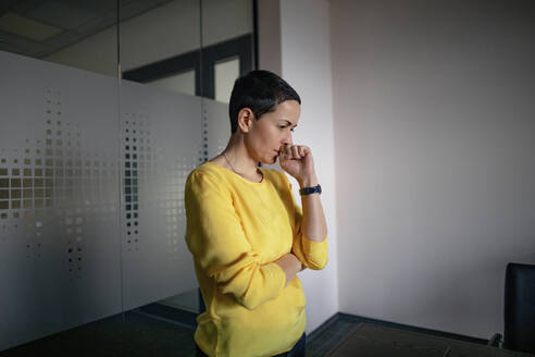 Businesswoman thinking while standing in office - OGF01010