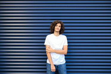 Caucasian young man standing in front of blue shutter - AODF00374