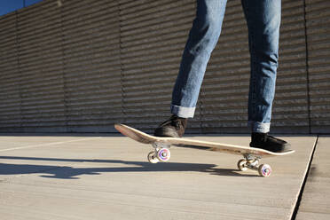 Young man skateboarding on hardwood floor during sunny day - AODF00385