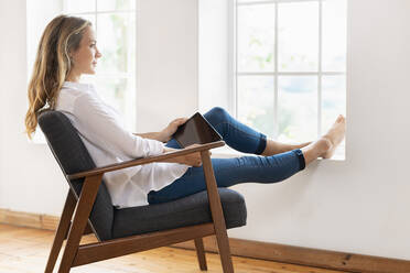Blond woman contemplating while sitting on armchair at home - SBOF03383